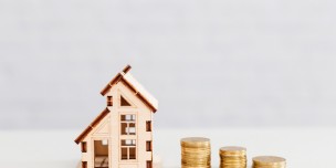 Stacked coins and wooden home