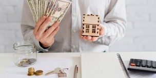 Realtor with money and wooden house