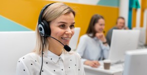 Blond woman working in a call center with headphones and computer